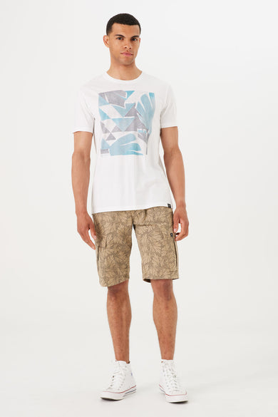 T-shirt à manches courtes blanc de GARCIA, avec motif graphique et porté avec un short à motifs de feuilles et des baskets montantes.

