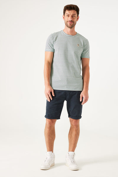 T-shirt à manches courtes blanc à rayures par GARCIA, porté avec un short bleu marine et des chaussures blanches montantes.