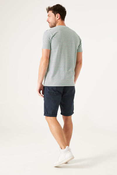 T-shirt à manches courtes blanc de GARCIA, à rayures horizontales, porté avec un short bleu marine et des baskets blanches.