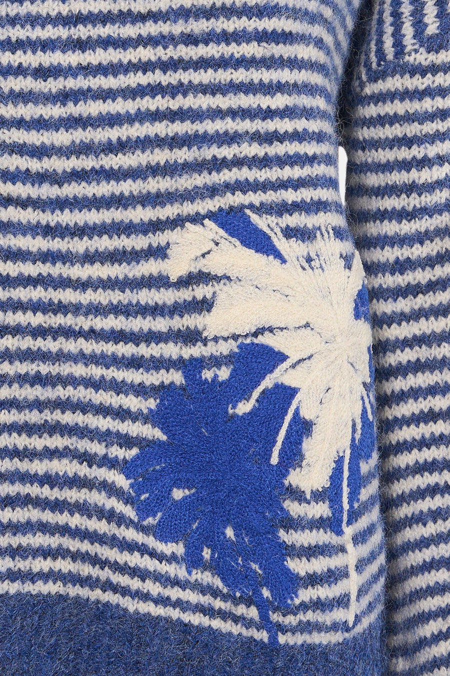 Pull à col rond bleu d'ADORE, à rayures horizontales avec un motif floral blanc et bleu.