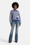 Pull à col rond bleu d'ADORE, rayures horizontales avec motif floral sur le devant, porté avec un jean évasé.
