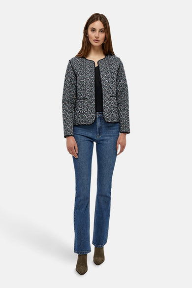 Jean évasé bleu moyen de Peppercorn, porté avec un veste à motif floral et des bottines marron.
