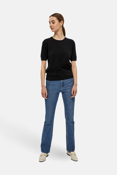 Pull noir à col rond de PEPPERCORN, porté avec un jean bleu et des mocassins crème.
