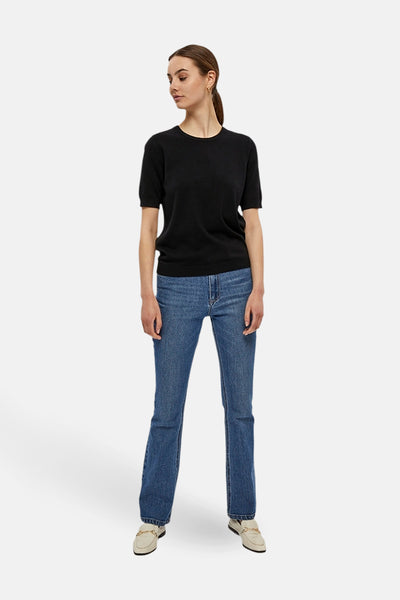 Pull noir à col rond de PEPPERCORN, porté avec un jean bleu et des mocassins crème.