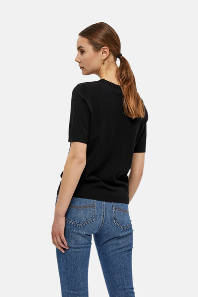 Pull noir à col rond de PEPPERCORN, porté avec un jean bleu et des boucles d'oreilles dorées, vue de dos.
