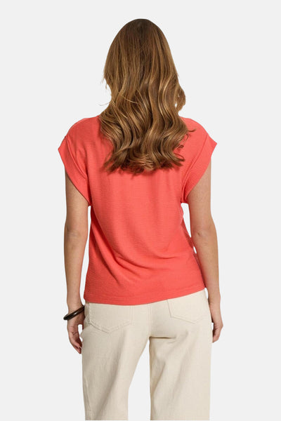 T-shirt corail à manches courtes de PEPPERCORN, avec un tissu texturé, porté avec un pantalon écru.