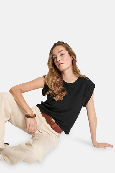 T-shirt noir à manches courtes de PEPPERCORN, porté avec un pantalon beige et une ceinture marron.
