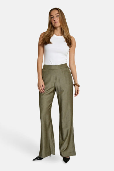Kaki broek van PEPPERCORN, rechte pasvorm, gedragen met een witte tanktop en zwarte puntige schoenen.
