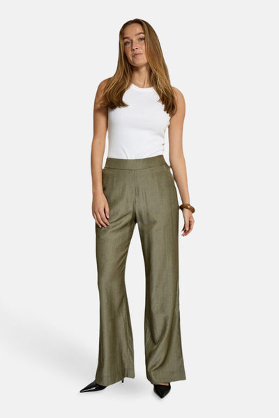 Kaki broek van PEPPERCORN, rechte pasvorm, gedragen met een witte tanktop en zwarte puntige schoenen.