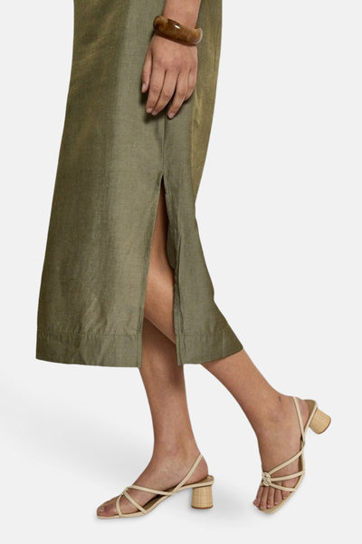 Robe kaki by PEPPERCORN avec une fente, portée avec des sandales à talons beige et un bracelet marron.