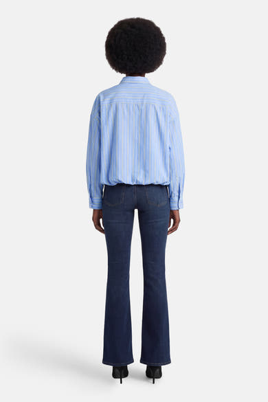 Chemise à manches longues bleue à rayures par ADORE, vue de dos portée avec un jean foncé évasé et des talons noirs.
