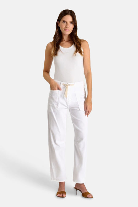 Jean blanc en denim par Le Temps des Cerises, porté avec un débardeur blanc et des mules marron.