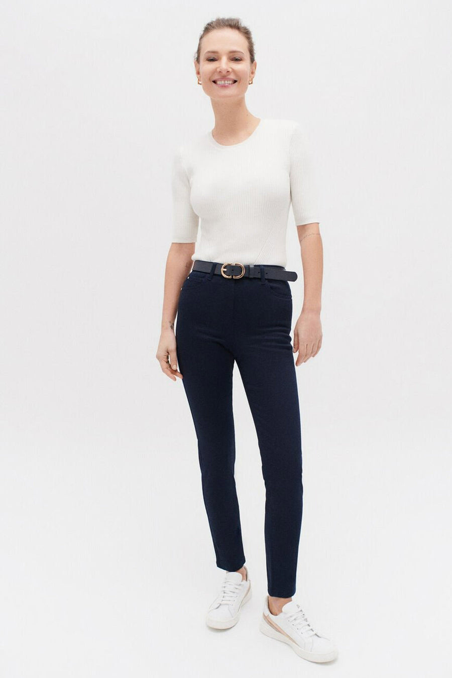 Gekleurde blauwe broek van CAROLL, gedragen met een zwarte riem met gouden gesp en witte sneakers.