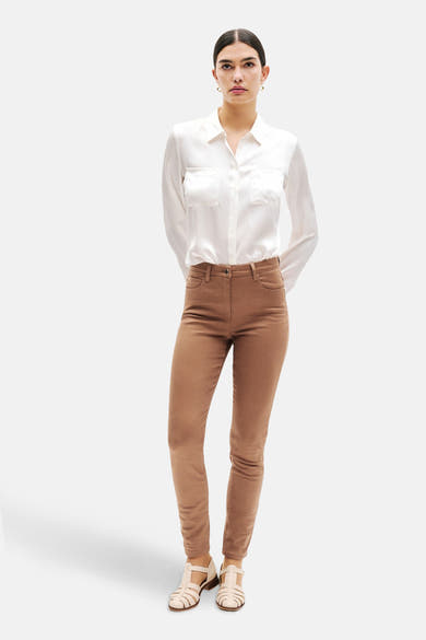 Cognac kleurige broek van CAROLL, gedragen met een wit overhemd met zakken en sandalen.
