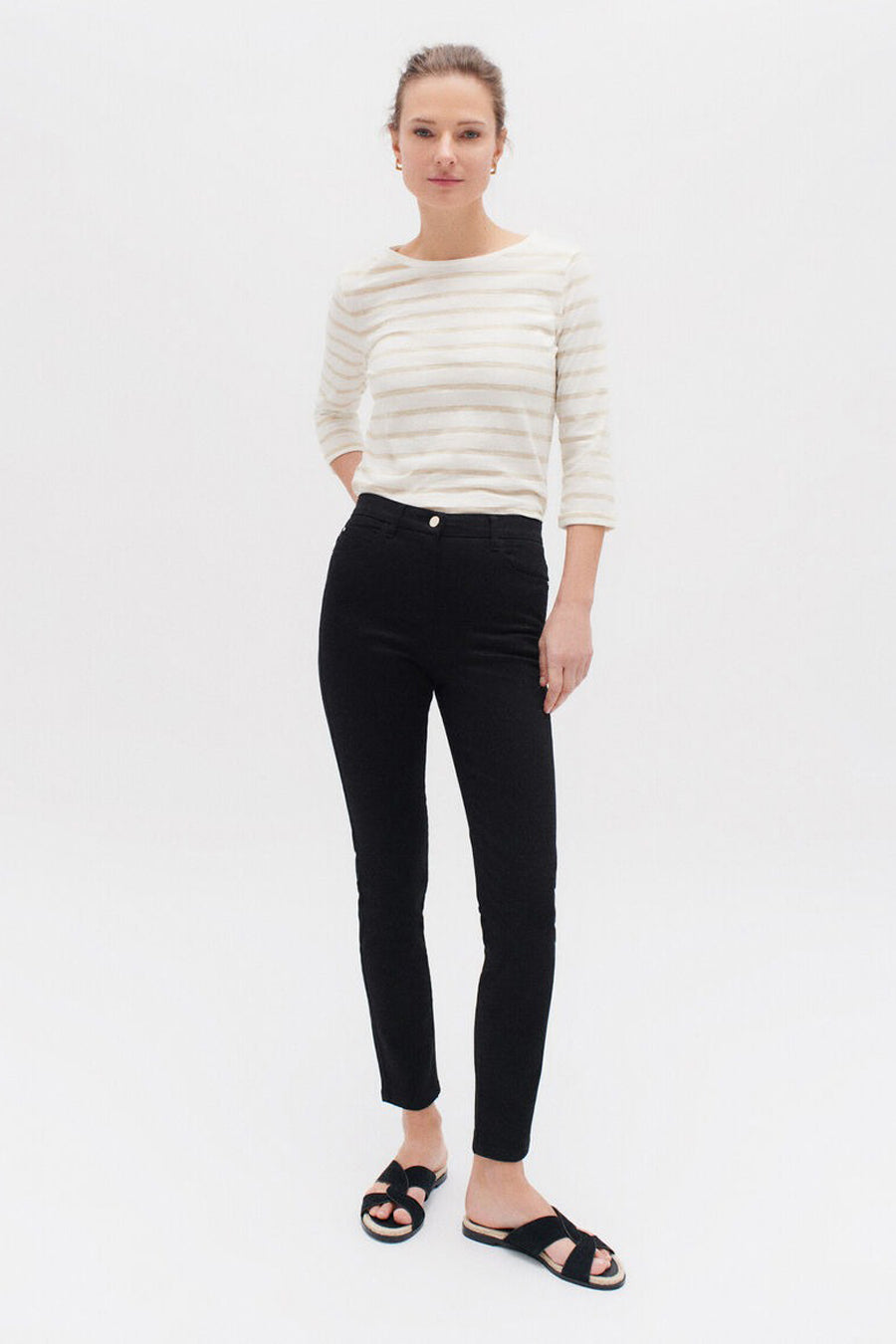 Zwarte broek van CAROLL, skinny fit, gedragen met een gestreept T-shirt en zwarte sandalen.