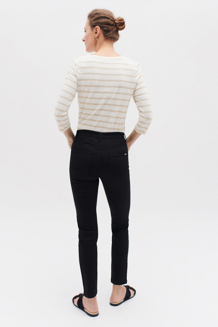 Zwarte CAROLL broek, slim fit, gedragen met een gestreept T-shirt en platte sandalen.