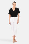 Pantalon chino 7/8 blanc de CAROLL, porté avec un t-shirt noir et des sandales dorées.
