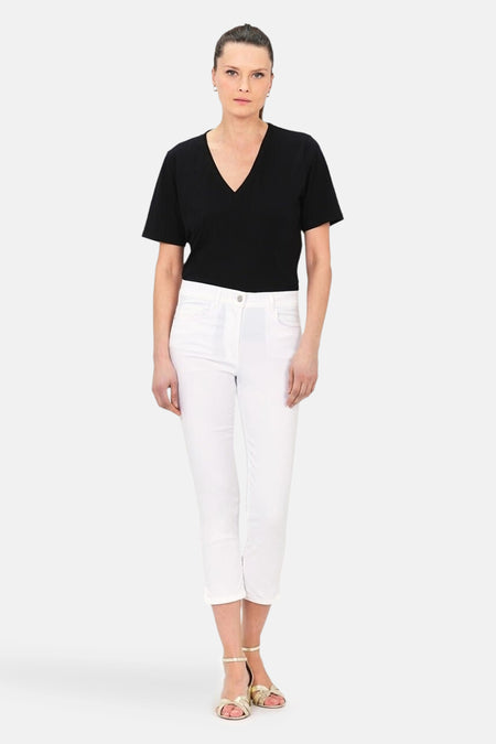 Witte 7/8 chino van CAROLL, gedragen met een zwart T-shirt en gouden sandalen.