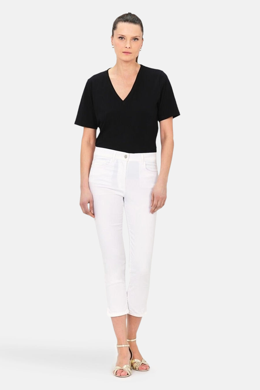 Pantalon chino 7/8 blanc de CAROLL, porté avec un t-shirt noir et des sandales dorées.