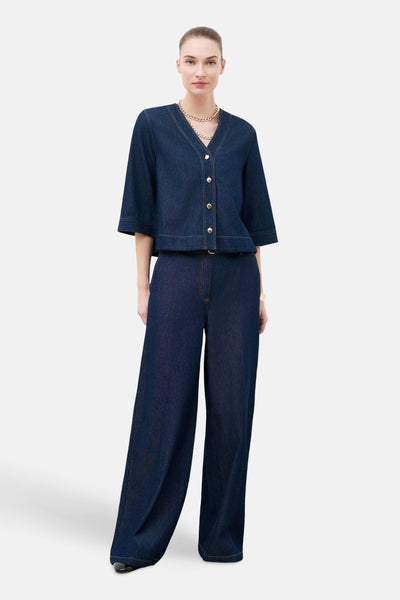 Ensemble en denim bleu foncé, style palazzo de CAROLL, avec une chaîne dorée au cou.
