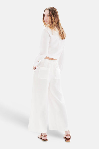 Pantalon blanc à poches de CAROLL, coupe large avec des sandales marron.