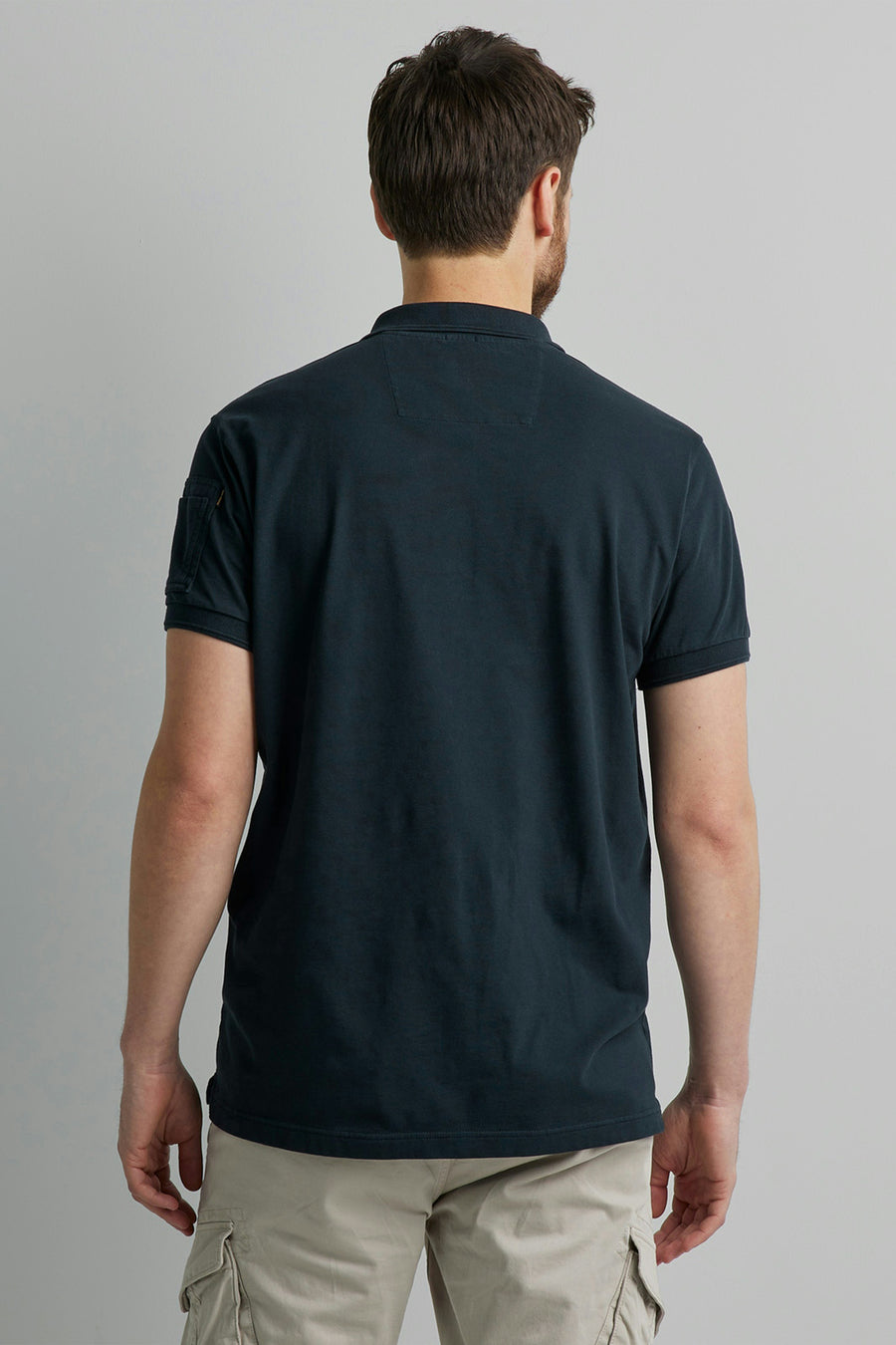 Polo bleu marine de Pme Legend, avec poche sur la manche, porté avec un pantalon cargo beige, vue de dos.
