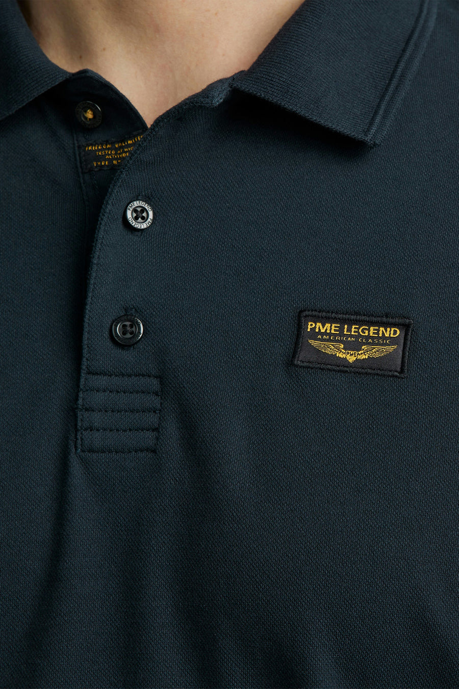 Polo bleu marine de PME Legend avec un col classique, des boutons griffés et un écusson logo sur la poitrine.
