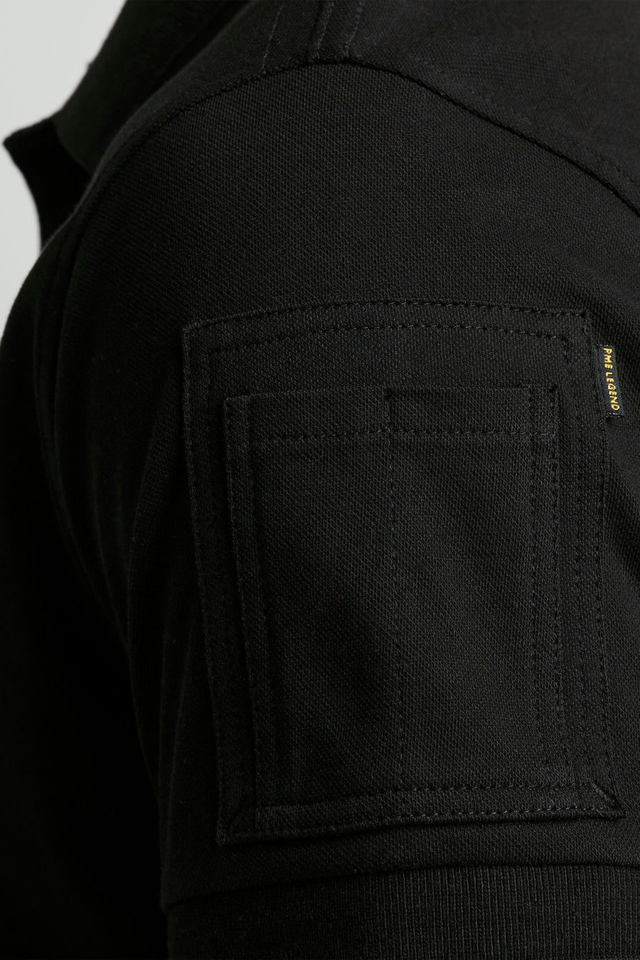 Polo noir de Pme Legend, avec une poche plaquée sur la poitrine.