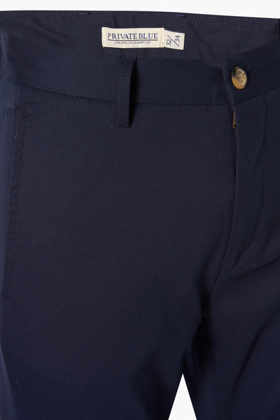 Pantalon coloré bleu marine de PRIVATE BLUE, avec bouton marron et détail de taille.