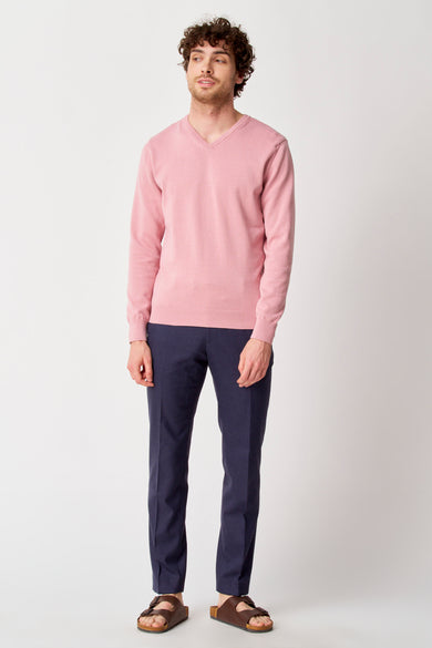 Roze V-hals trui van PRIVATE BLUE, gedragen met een marineblauwe broek en bruine sandalen.