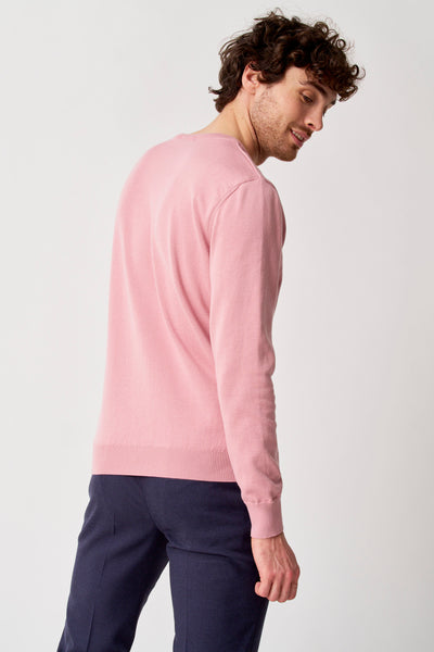 Pull à col en V rose de PRIVATE BLUE, porté avec un pantalon bleu marine.