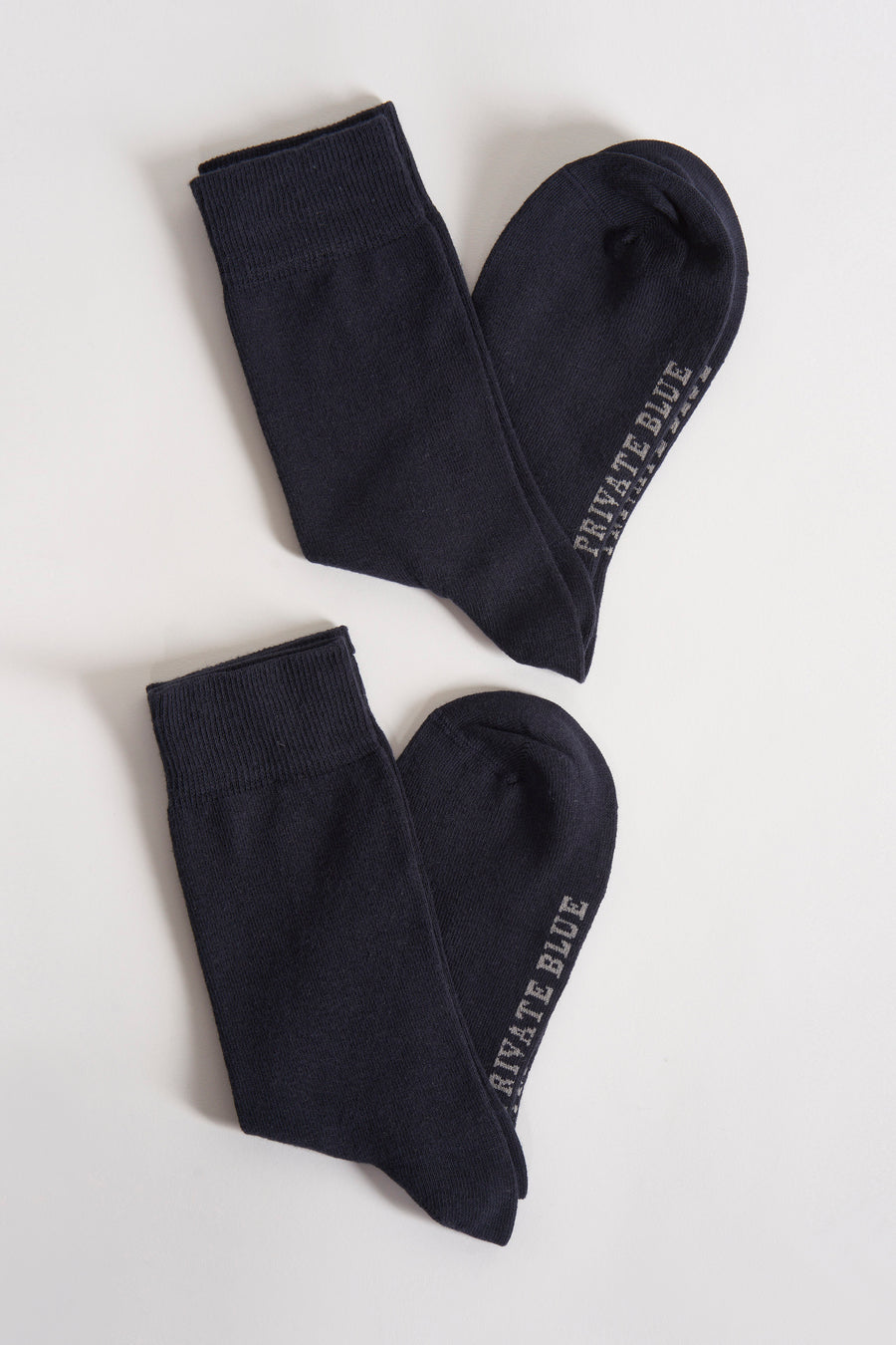 Blauwe sokken van PRIVATE BLUE, platliggend op een witte achtergrond.
