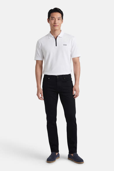 Pantalon coloré noir de PRIVATE BLUE, porté avec un polo blanc et des mocassins bleus marine.