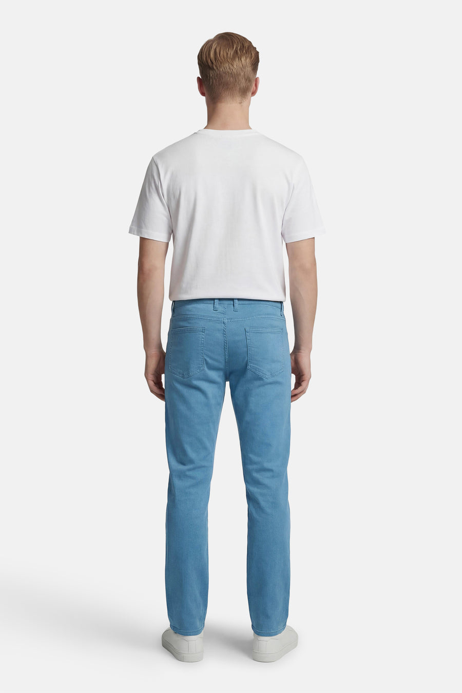 Gekleurde blauwe broek van PRIVATE BLUE, rechte pasvorm, gedragen met een wit T-shirt en witte schoenen.