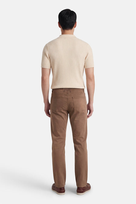 Pantalon coloré brun de PRIVATE BLUE, porté avec un polo en maille côtelée et des chaussures bateau.