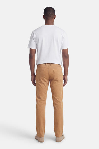Beige kleurrijke broek van PRIVATE BLUE, van achteren gezien, gedragen met een wit T-shirt en suède schoenen.