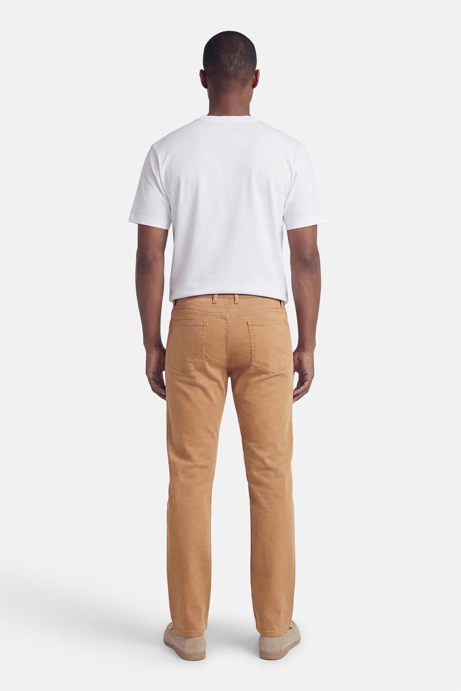 Beige kleurrijke broek van PRIVATE BLUE, van achteren gezien, gedragen met een wit T-shirt en suède schoenen.