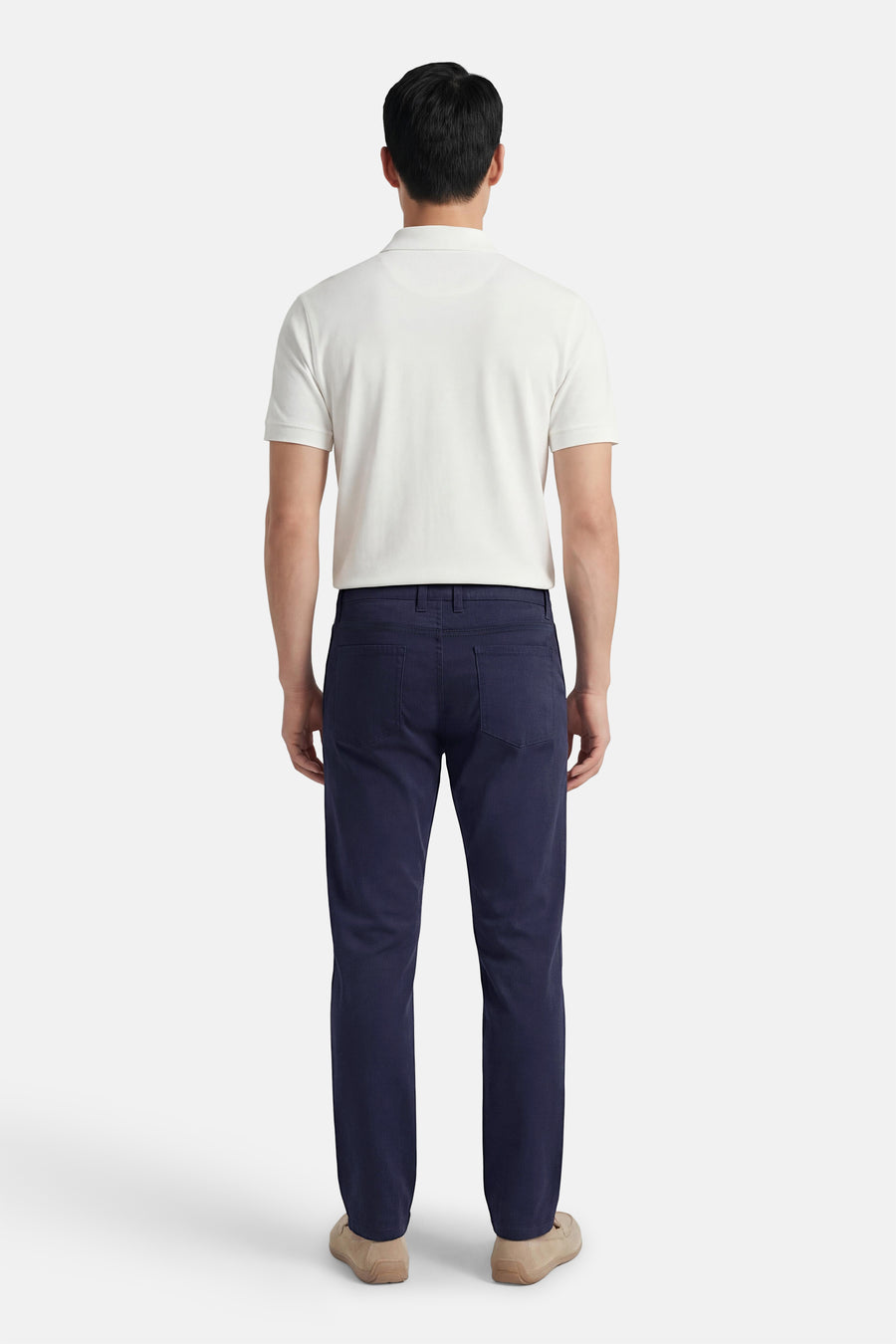 Gekleurde blauwe broek van PRIVATE BLUE, van achteren gezien, gedragen met een witte polo en lichtbruine loafers.