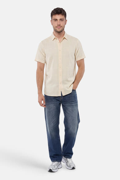 Chemise jaune à manches courtes de PME LEGEND avec un motif quadrillé subtil, portée par un homme avec un jean et des baskets.
