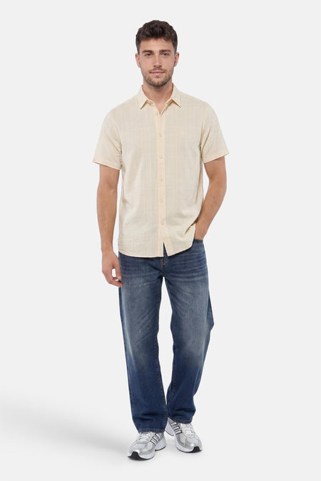 Chemise jaune à manches courtes de PME LEGEND avec un motif quadrillé subtil, portée par un homme avec un jean et des baskets.