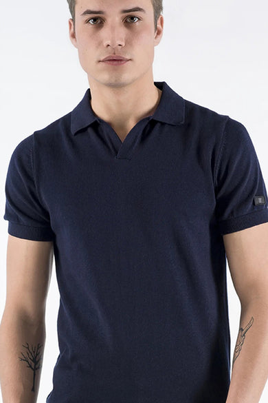 Polo bleu de PRESLY & SUN, manches courtes avec revers, porté par un homme avec des tatouages.
