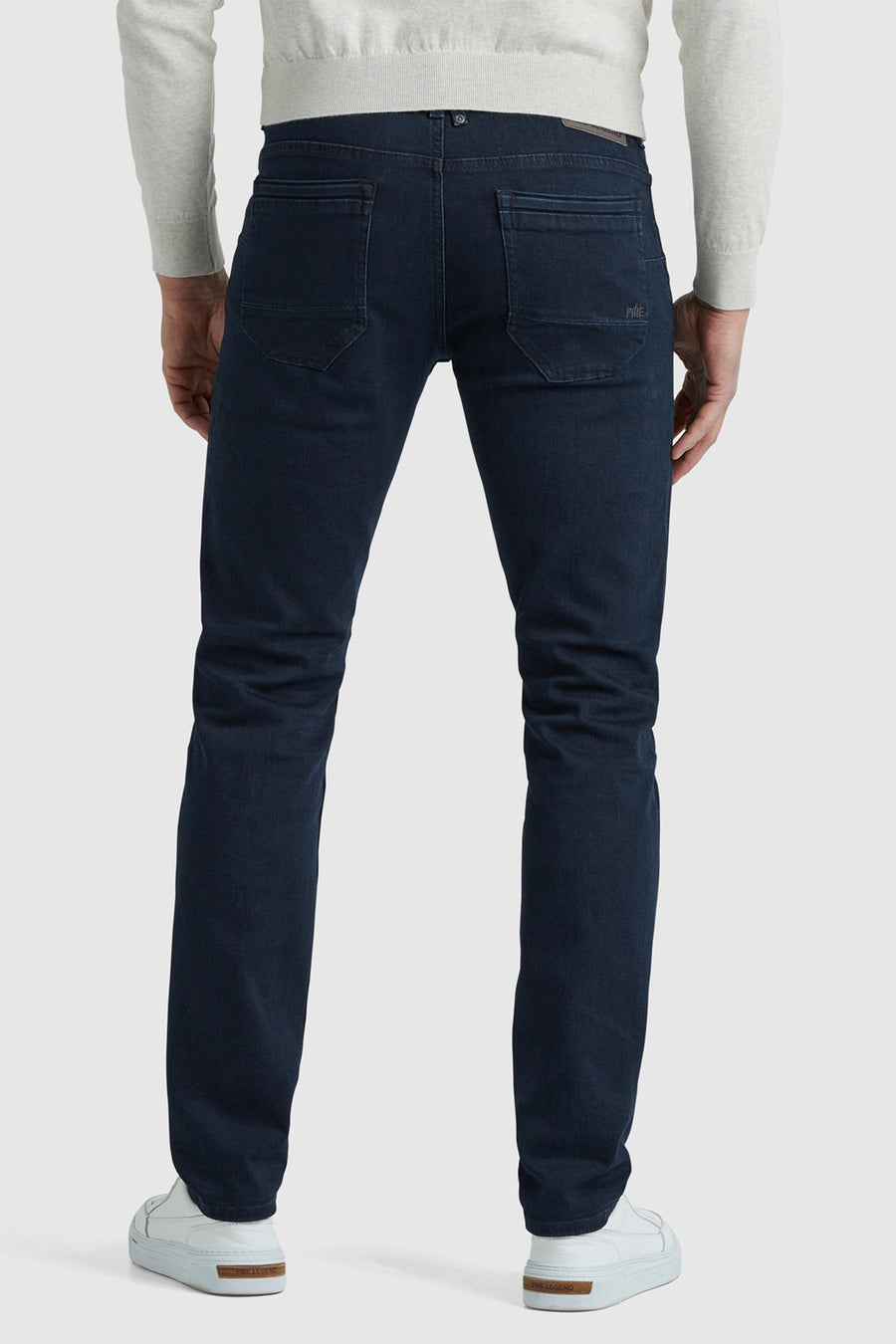 Rechte donkerblauwe jeans van PME Legend, vijfzakkenmodel, gedragen met een lichtgrijze trui en witte sneakers.
