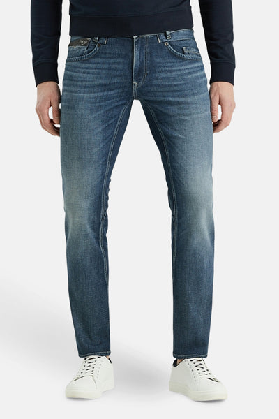 PME Legend blauwe tapered jeans met een klassieke pasvorm, gedragen met witte sneakers en een marineblauwe trui.