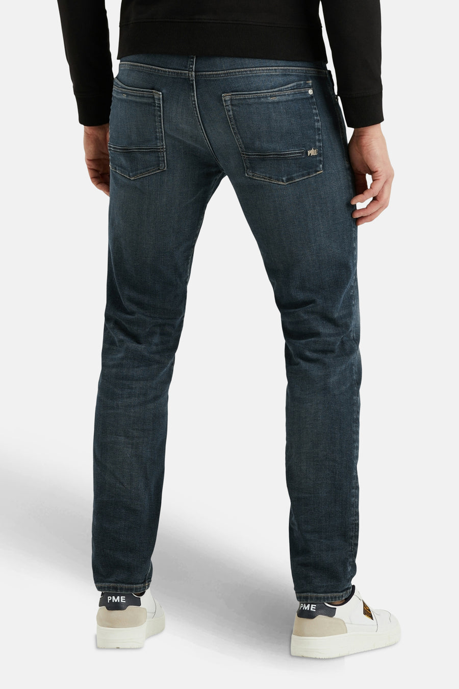 Jean droit en denim bleu foncé de PME Legend, avec poches arrière et chaussures blanches.