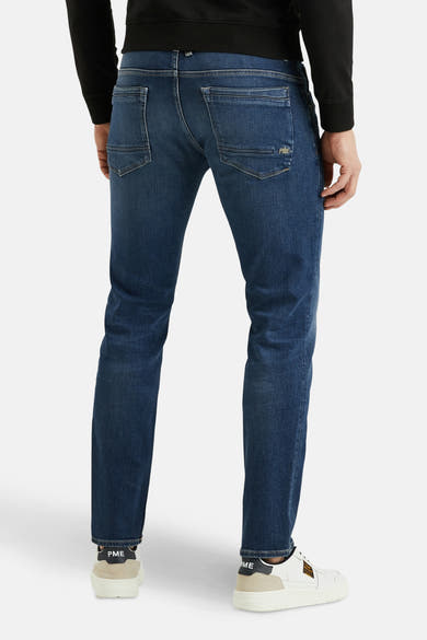Jean droit bleu moyen de PME Legend, avec poches arrière et chaussures de sport blanches.