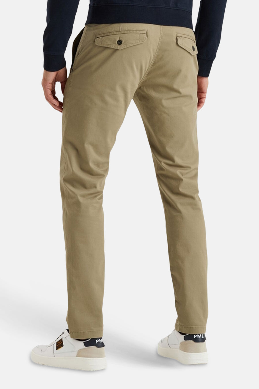 Beige chino van PME Legend, met achterzakken met knoopsluiting, gedragen met een marineblauwe trui en witte sneakers.
