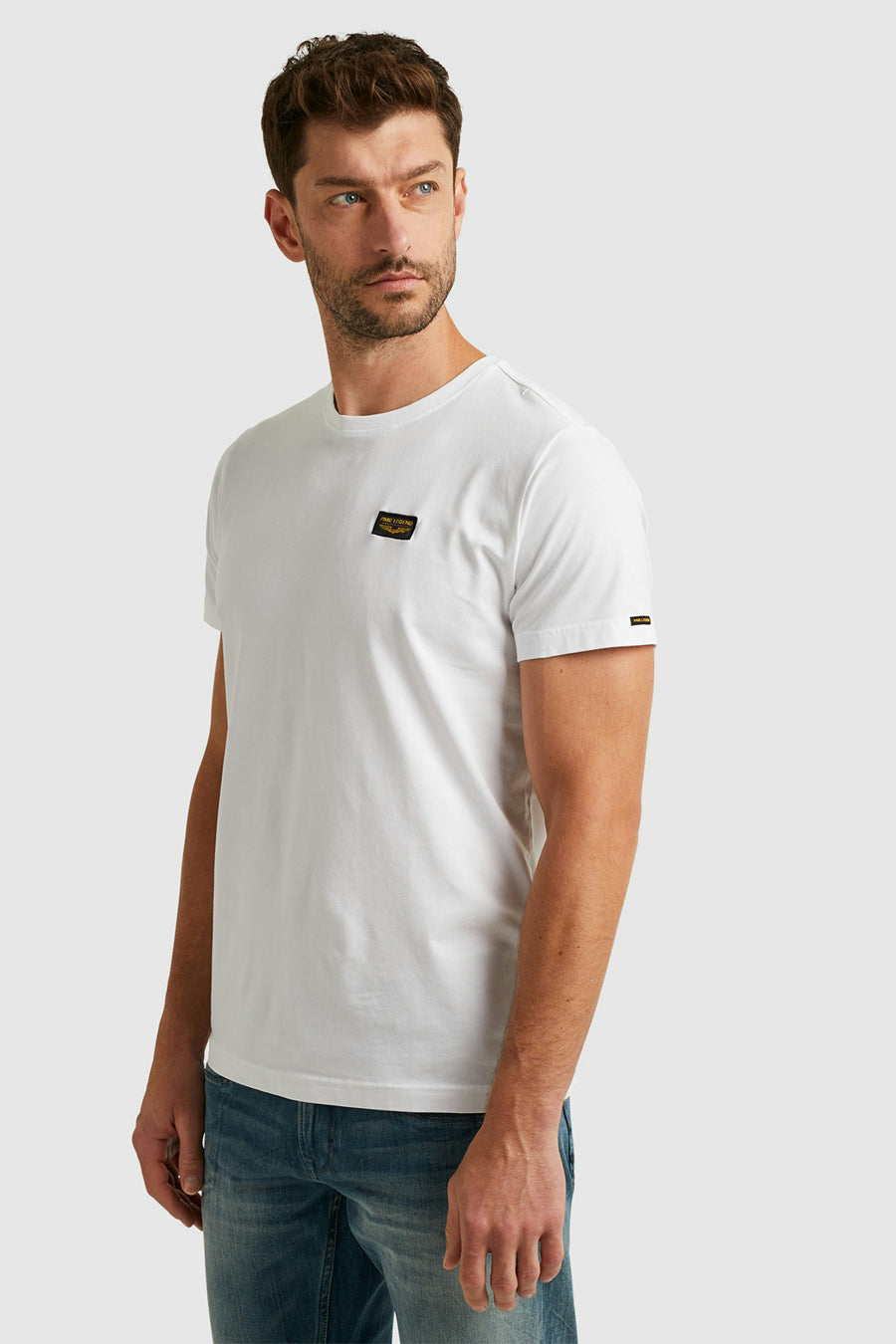 T-shirt blanc de Pme Legend, avec écusson sur la poitrine et porté avec un jean.