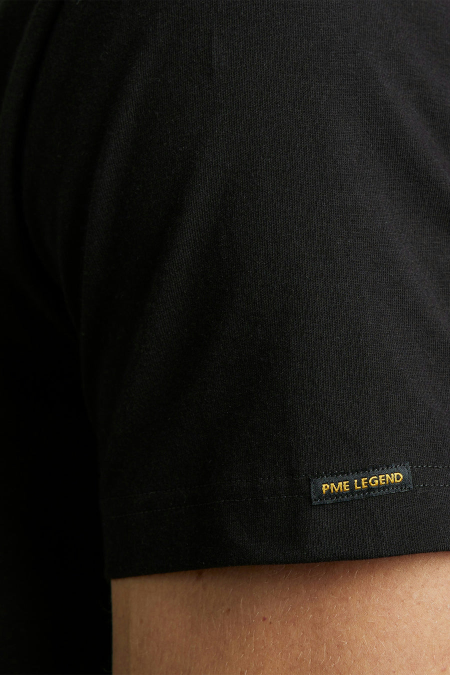 T-shirt noir de Pme Legend, avec étiquette de la marque sur la manche.
