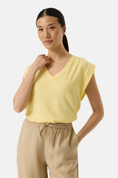 Top jaune de GARCIA, col en V, sans manches, avec détails brodés sur les épaules, porté avec un pantalon beige.