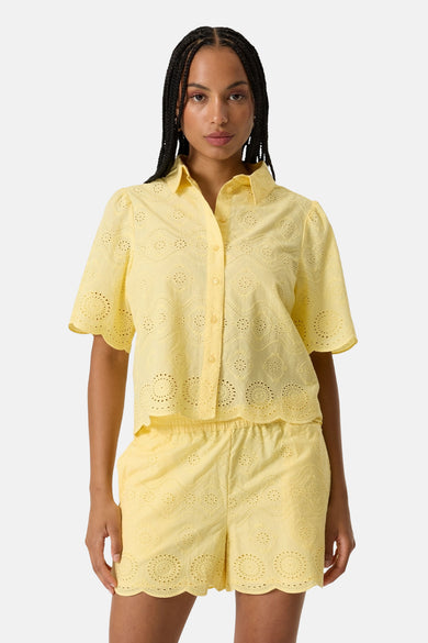 Chemise à manches courtes jaune de GARCIA en broderie anglaise avec col, manches bouffantes et ourlet festonné, portée avec un short assorti.